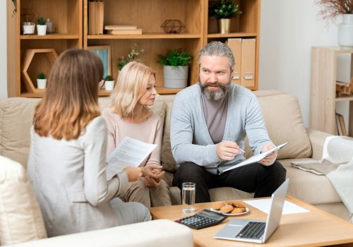 Bearded man looking through paper while consulting with real estate agent